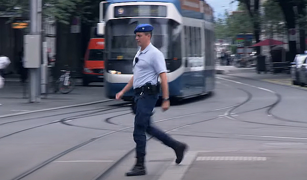 SECURITAS Mitarbeitender überquert die Bahnhofstrasse in Zürich vor der Tramhaltestelle am Paradeplatz